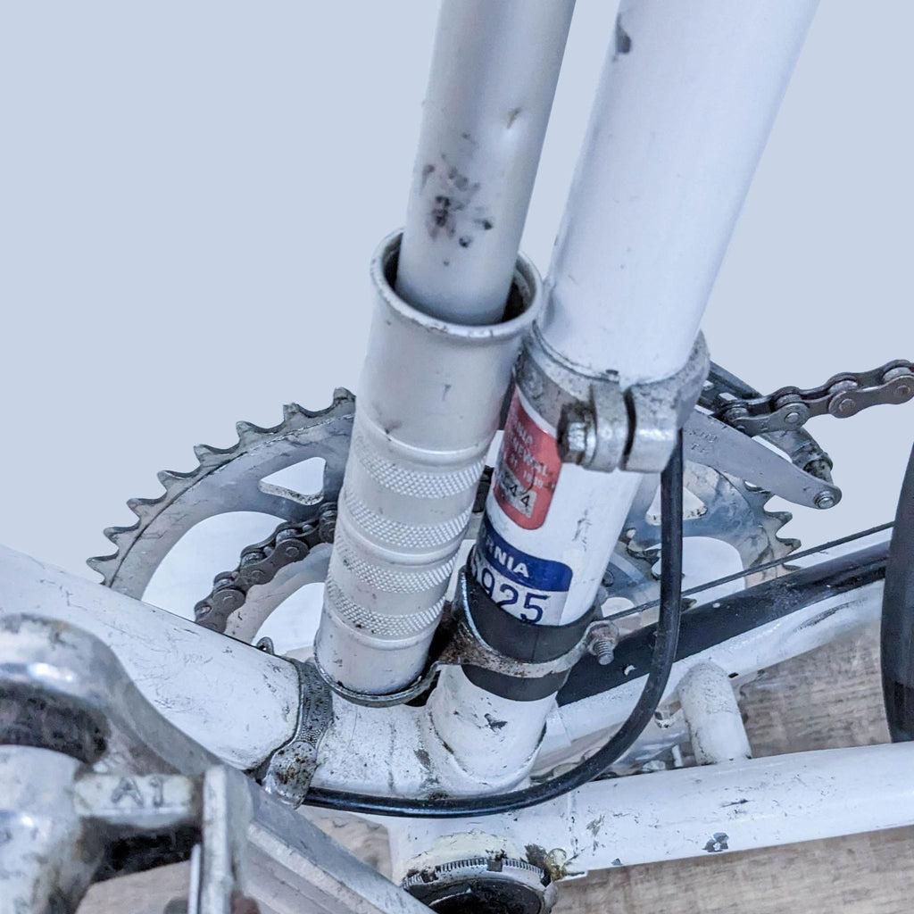 Alt text 2: Close-up of the gears and bottom bracket of a white Reperch bicycle showing detail of the chain and frame.