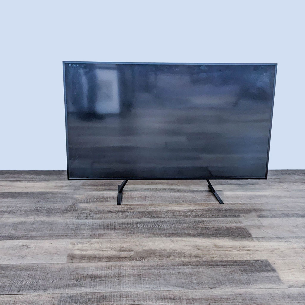 Samsung TV on a wooden floor, displaying a blank screen.