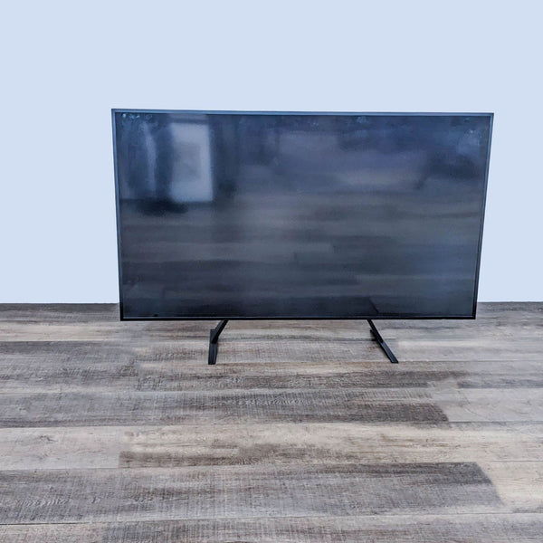 Samsung TV on a wooden floor, displaying a blank screen.