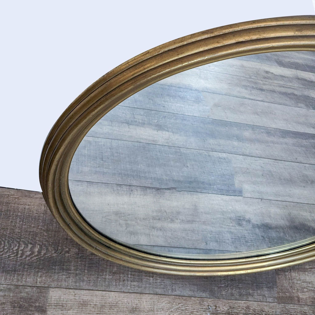 2. Close-up of the gold wood framed edge on a round Reperch mirror, showing its classic design.  