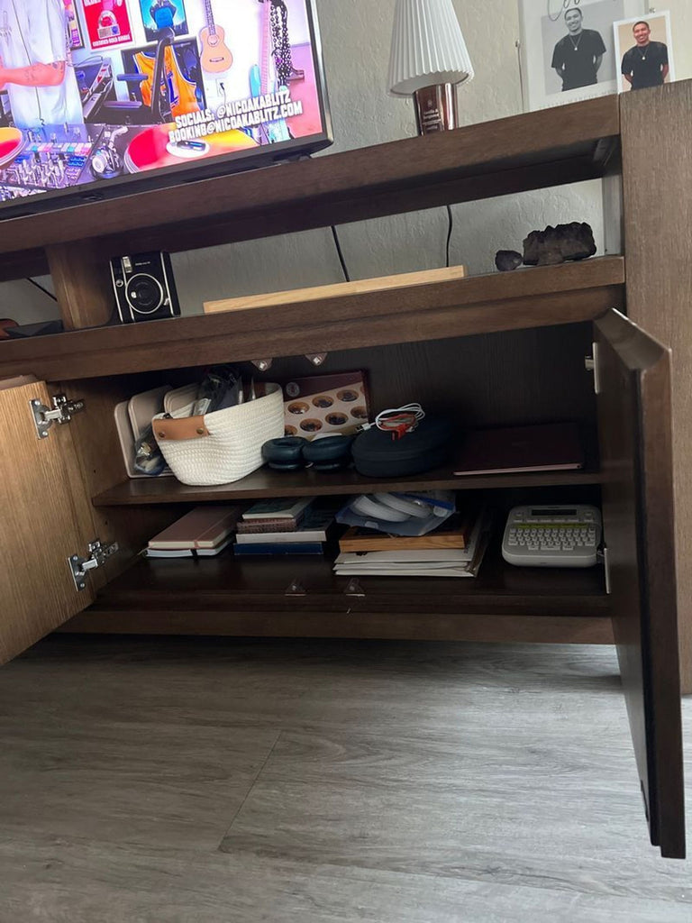 3. Open cabinet of a Living Spaces entertainment center displaying organized storage of books, baskets, and electronics.