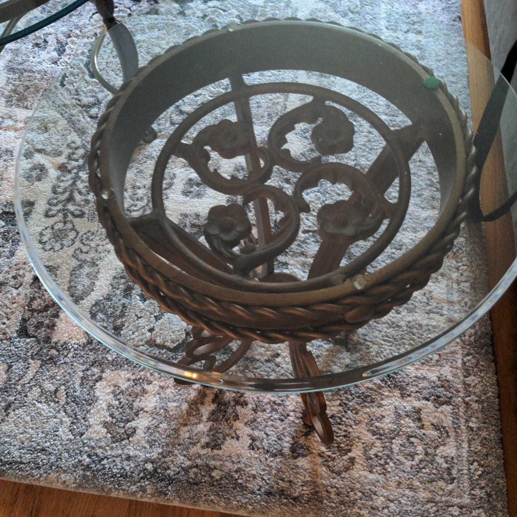 1. Round glass top end table with ornate floral metalwork seen from above on a patterned carpet.