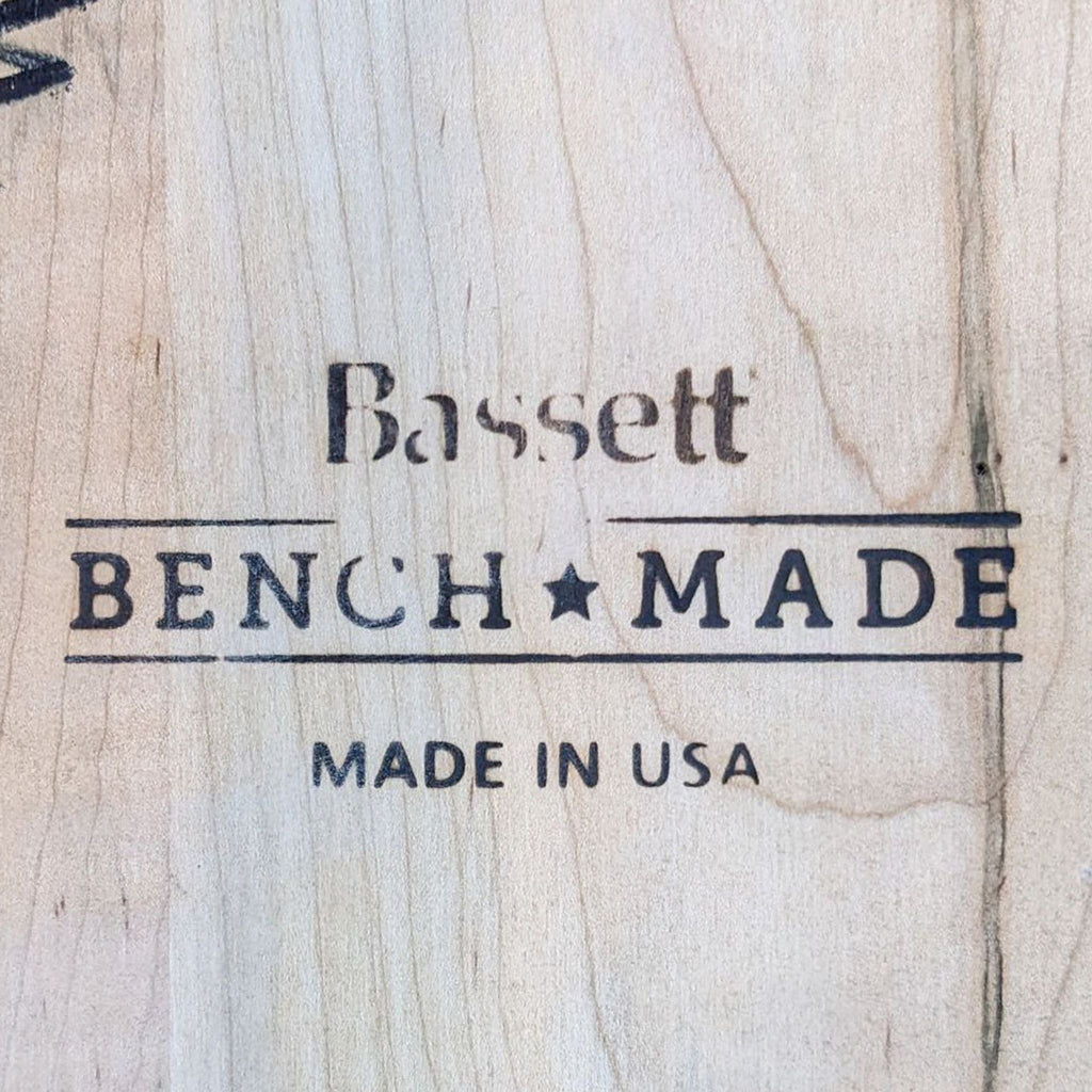 Close-up of Bassett Bench Made logo on wood, indicating artisan craftsmanship and USA origin.