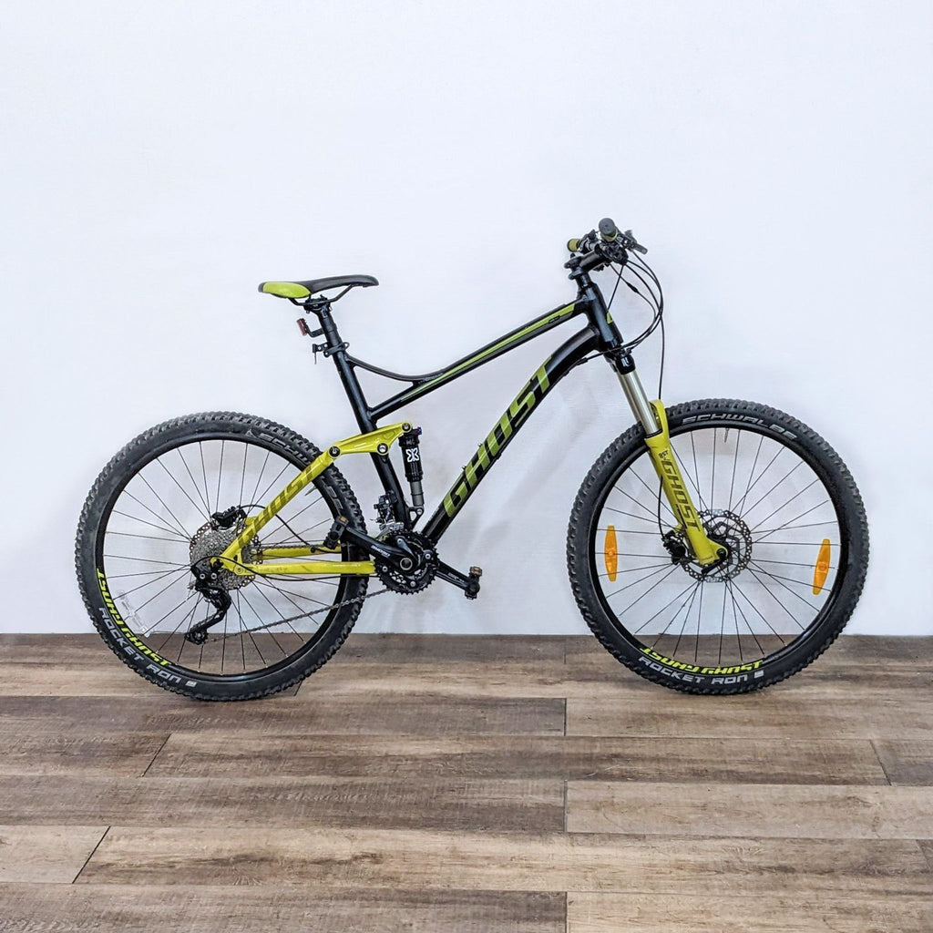 Side view of a yellow and black mountain bike on a wooden floor, ideal for rugged terrain.