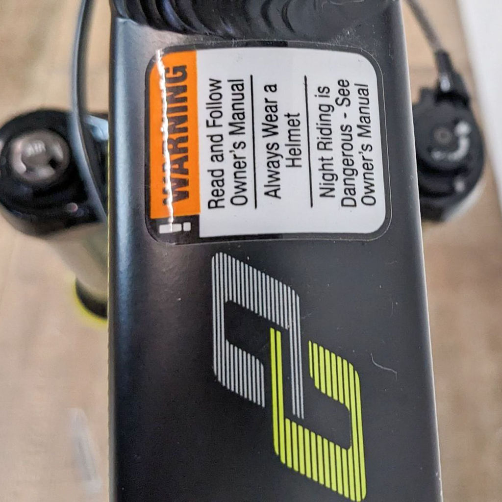 Close-up of a caution label on a mountain bike, highlighting safety instructions for riders.