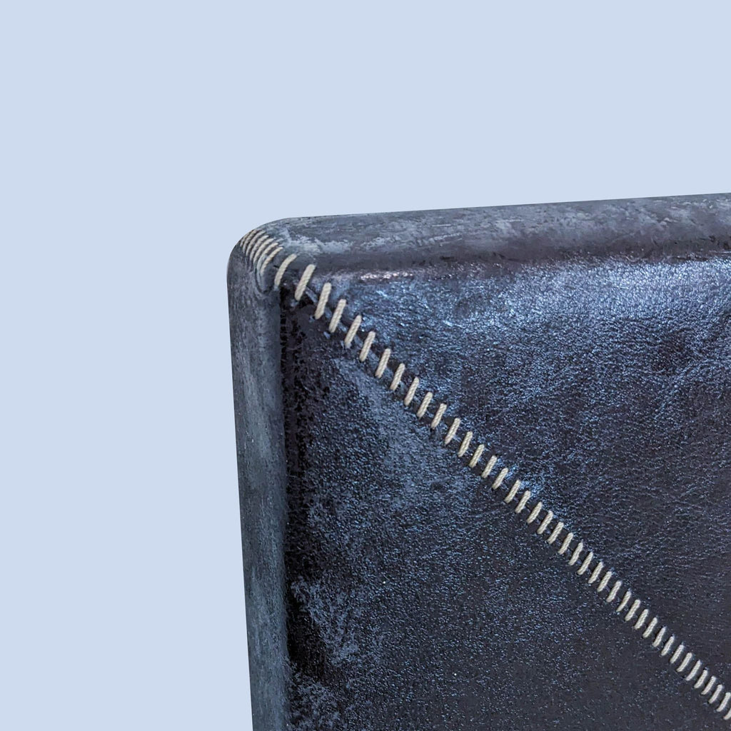 Close-up of leather-framed mirror corner, highlighting the detailed contrasting stitching.