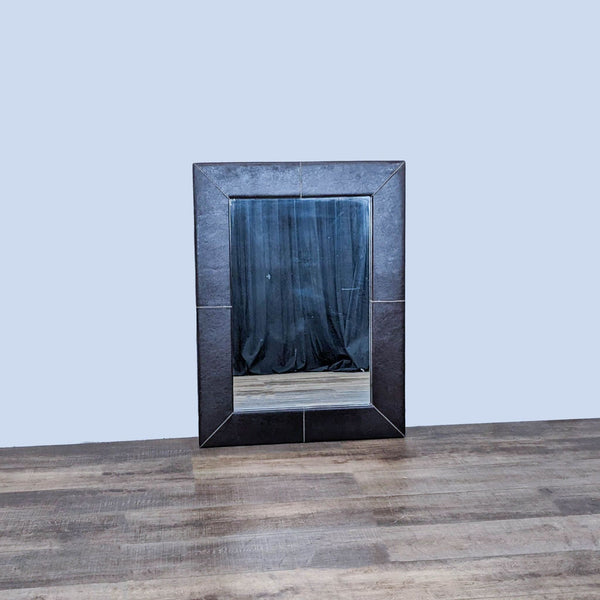 Contemporary rectangle mirror with leather frame and contrasting stitching on wooden floor.