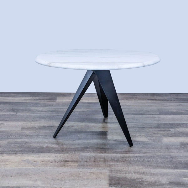 Round marble dining table with black steel base, featuring modern sculptural design. Brand: Reperch.