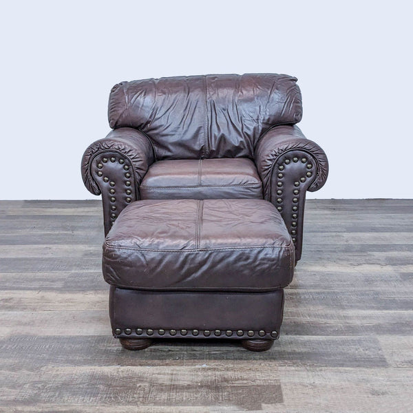 Reperch traditional leather lounge chair with ottoman, rolled arms, wood feet, and nailhead trim on gray flooring.