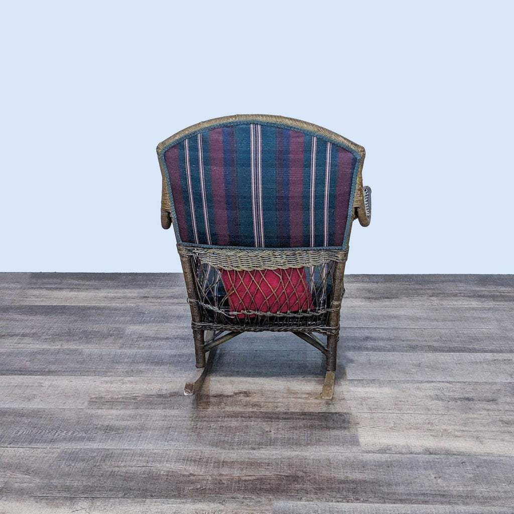 Rear view of a Reperch rattan rocking chair showcasing its high-back design and woven detailing, with striped cushion visible, against a wooden floor.