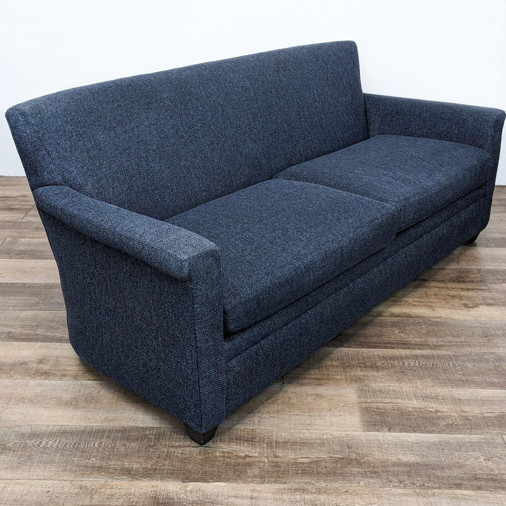 Side view of a blue loveseat from Crate & Barrel, highlighting its sleek lines and turned arms.