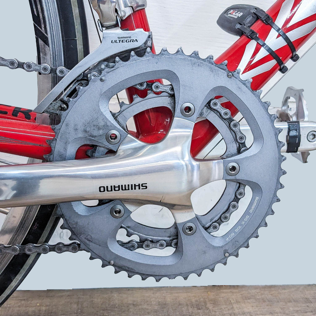 Close-up of an Eddy Merckx road bike's crankset and front derailleur, featuring Shimano Ultegra components and a red and black frame.