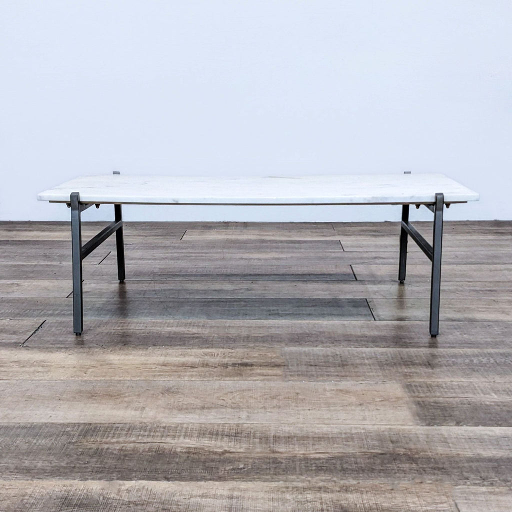 Marble slab coffee table with steel legs on wooden floor.