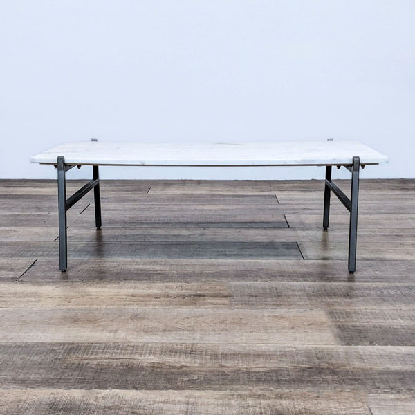 Marble slab coffee table with steel legs on wooden floor.