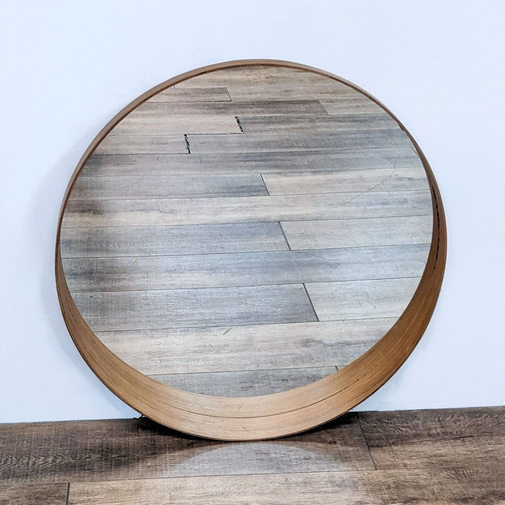 IKEA Stockholm round mirror with brass-finished metal frame, reflecting wood surface.