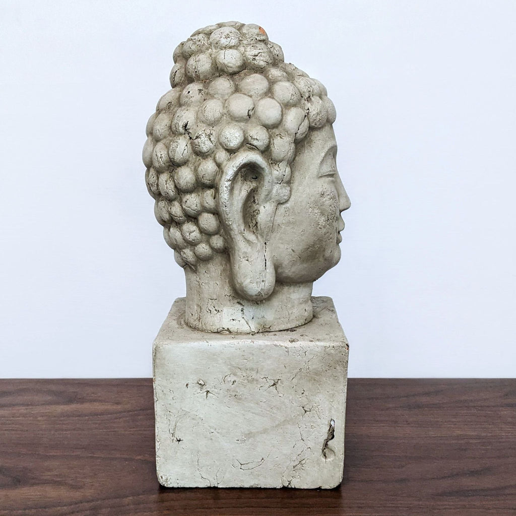 Side profile of a terra cotta Buddha sculpture with an aged finish.
