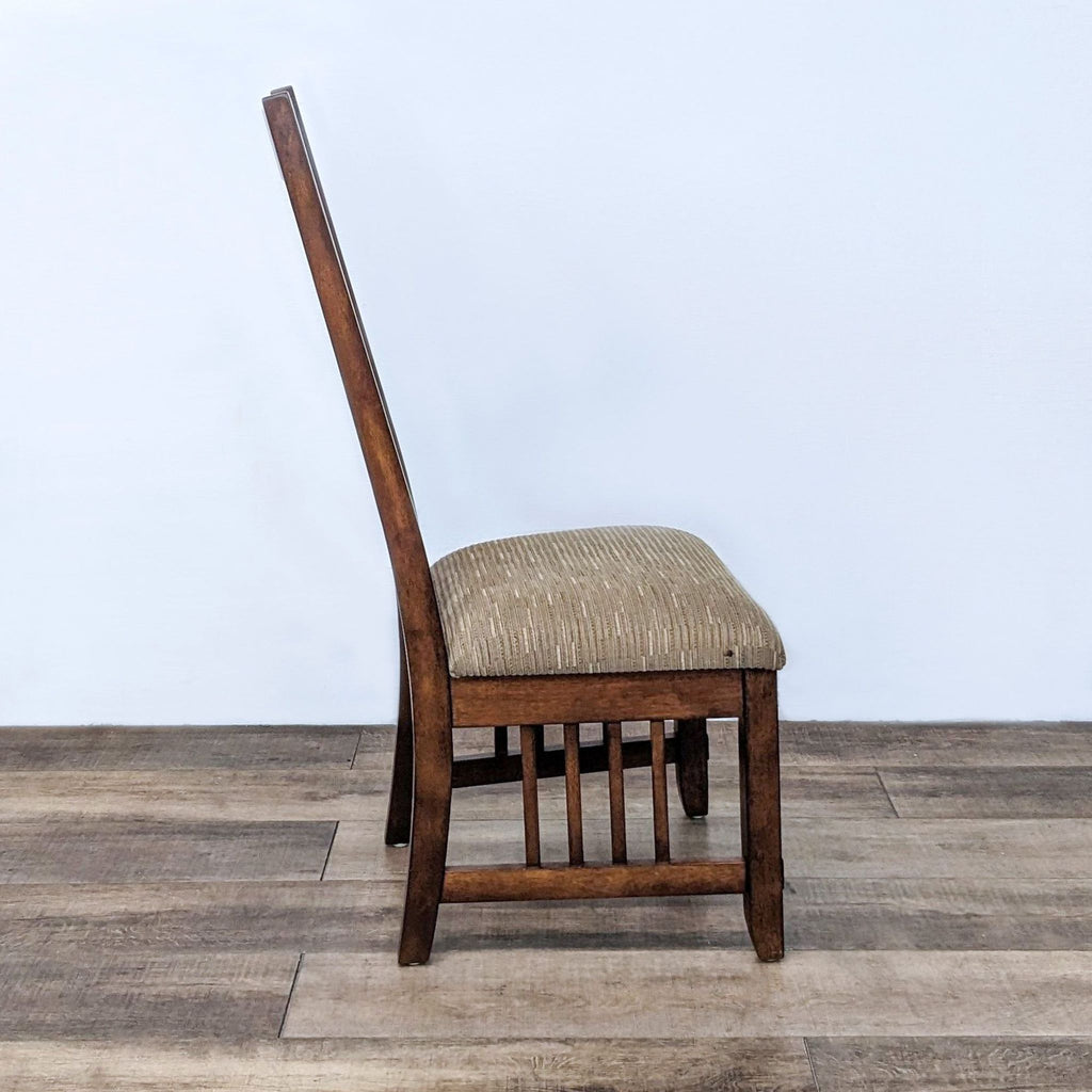 Side view of wooden chair with cushioned fabric seat and vertical slat backrest.