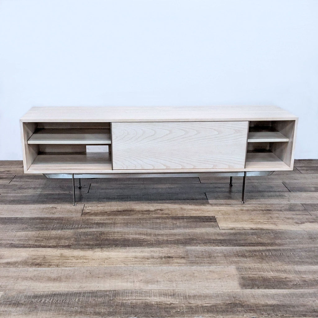 Open Room & Board entertainment center revealing adjustable shelves and stainless steel base against a wooden backdrop.