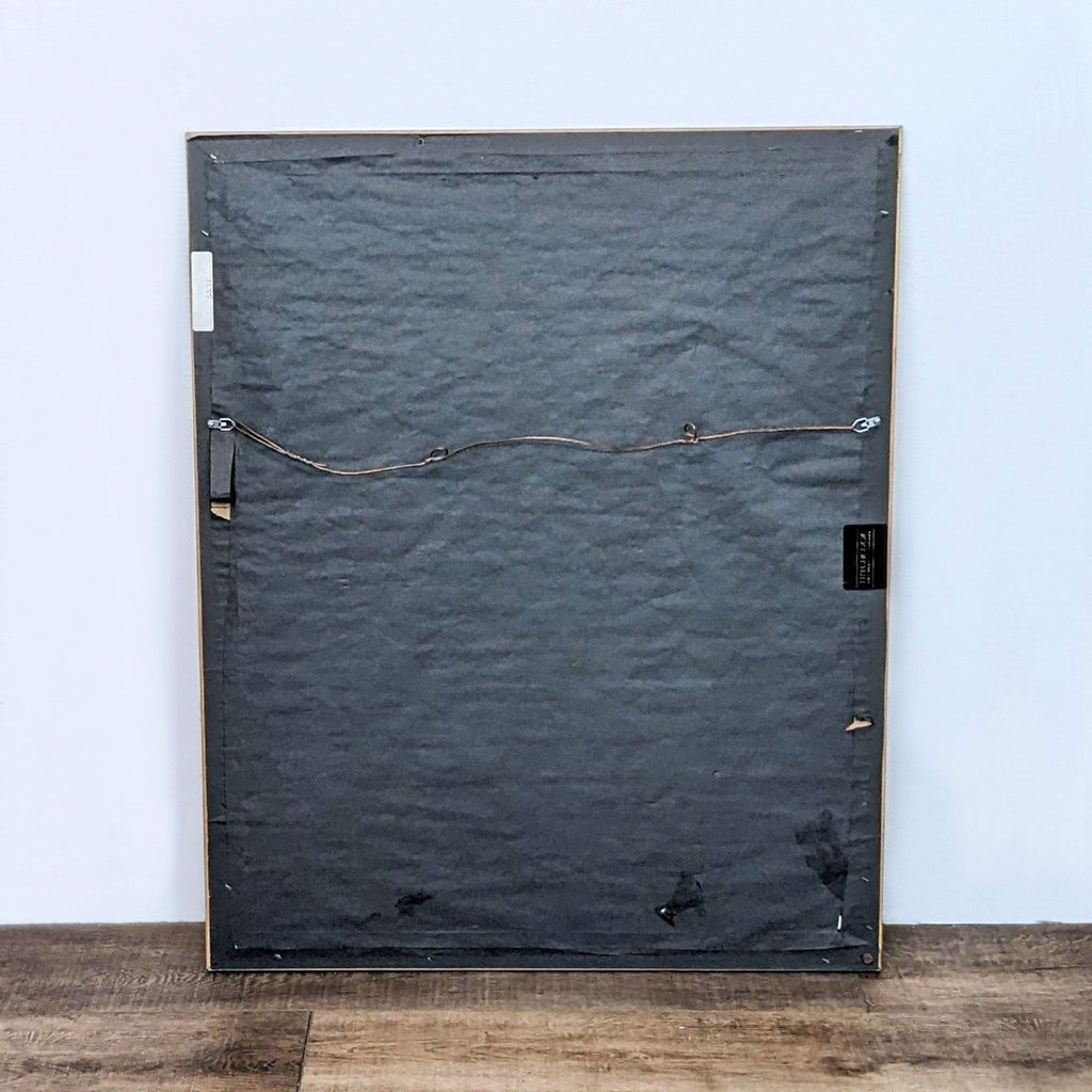 Back view of a framed artwork, showing mounting wire and frame.