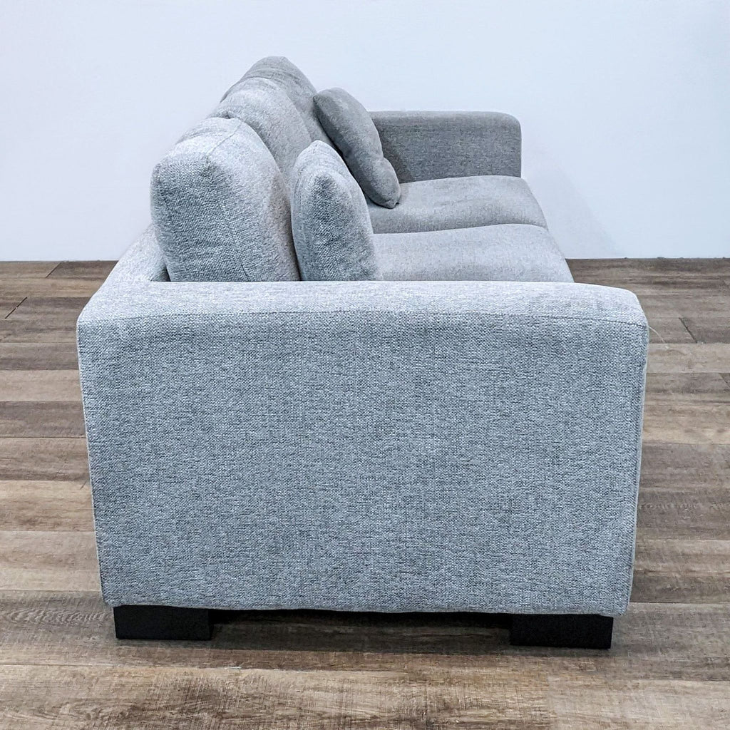 Side view of gray 3-seat Reperch sofa with plush cushions, square arms, and dark wood block feet.