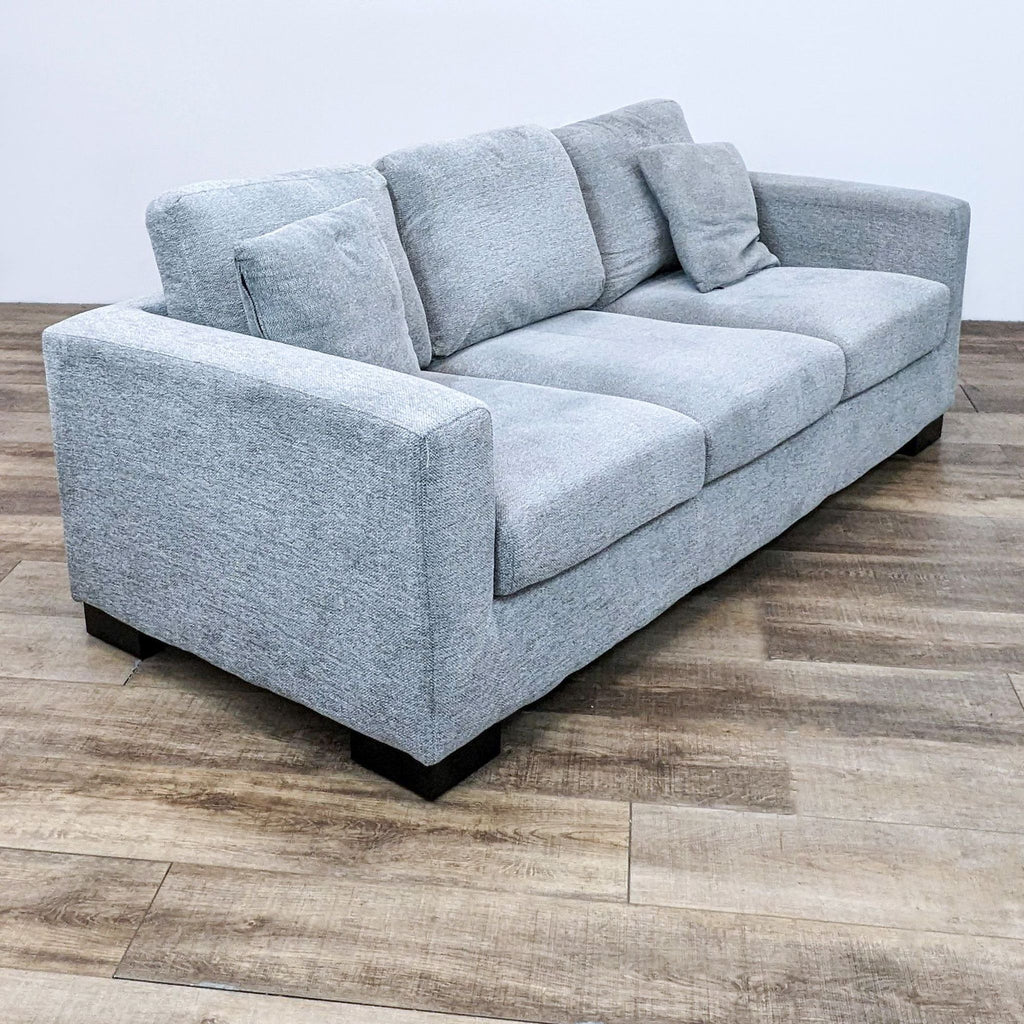 Reperch 3-seat sofa in gray fabric with square arms and plush cushions. Dark wood finish block feet.