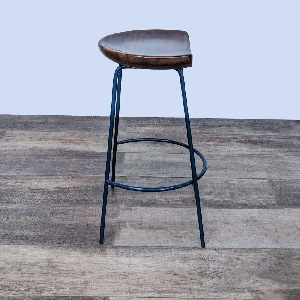 3. Modern West Elm stool featuring a dark wood seat and round black steel base, placed on rustic wooden flooring.