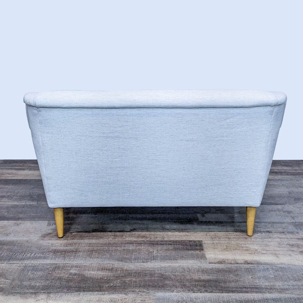 Button eye cream fabric sofa with slope arms and light wood legs.