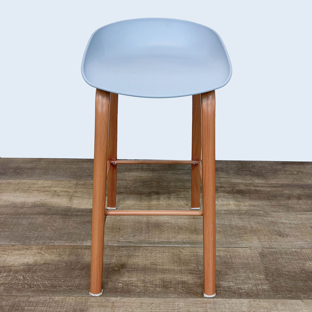 Molded gray barstool with wooden legs on a wood floor.  
