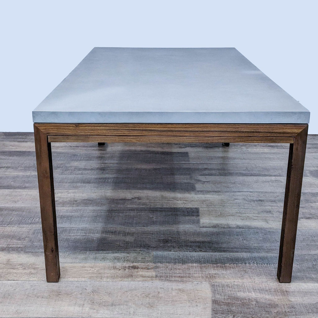 Concrete top dining table with walnut base, from Reperch, shown in Parsons style.