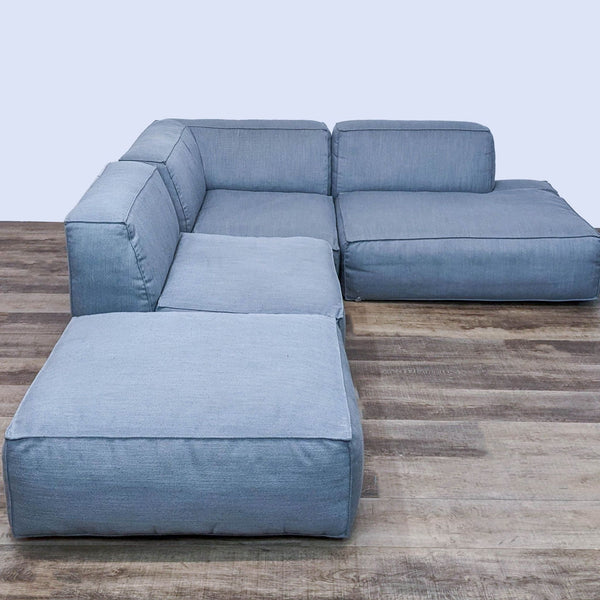 Gray four-piece sectional on wood floor, minimalistic design with self-piping details.