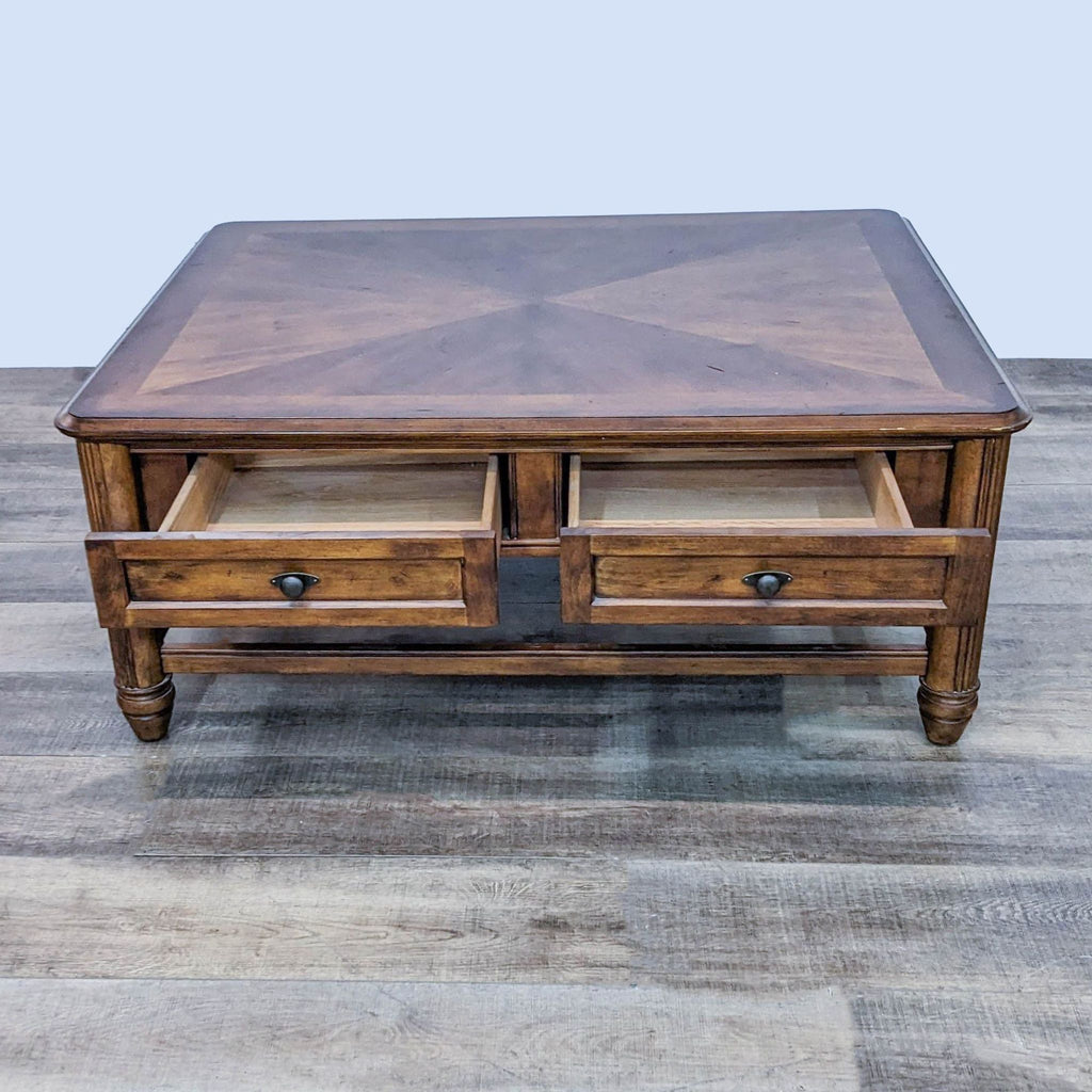 Classic Reperch coffee table with decorative inlay design and open drawers, set against a wooden backdrop.