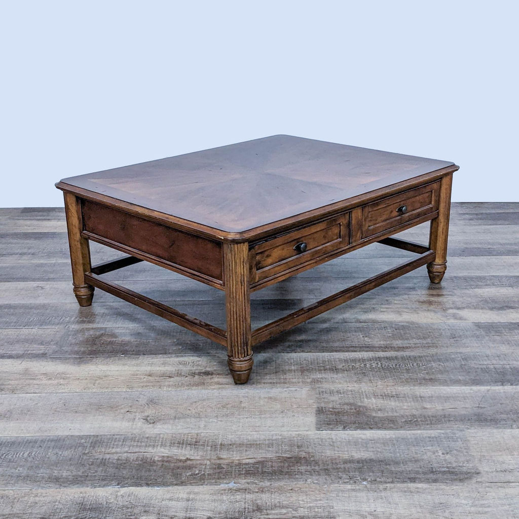 Reperch traditional square coffee table with inlaid top, drawers, and turned legs on a wooden floor.