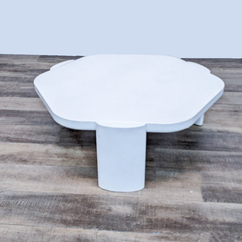 Pro-Living Asia modern white coffee table with a unique petal-shaped top and cylindrical base, on a wooden floor.