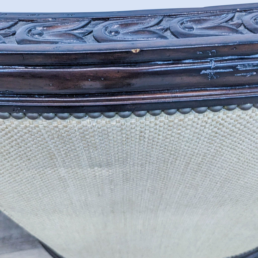 Close-up of a Marge Carson lounge chair detailing: striped fabric, nailhead trim, and carved wooden frame.