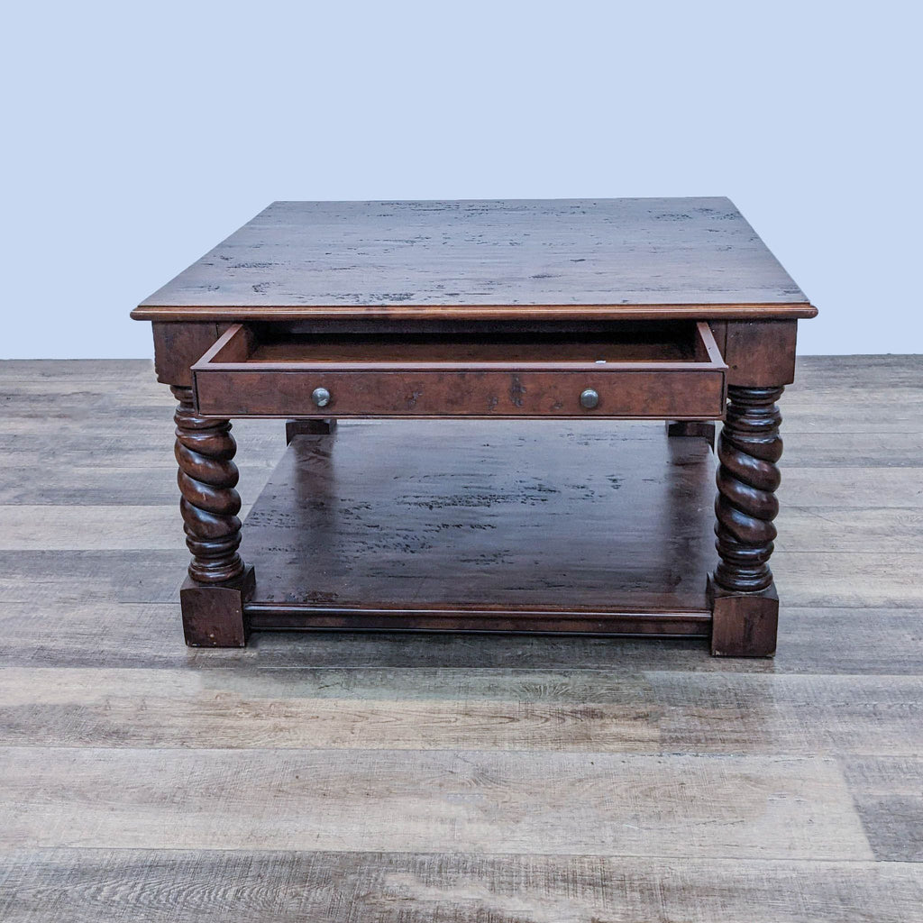 One-drawer Reperch coffee table with ornate legs, drawer partially open, against a neutral backdrop.
