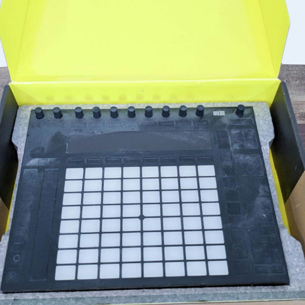 Ableton Push MIDI controller in original yellow packaging, device with grid pads and knobs visible.