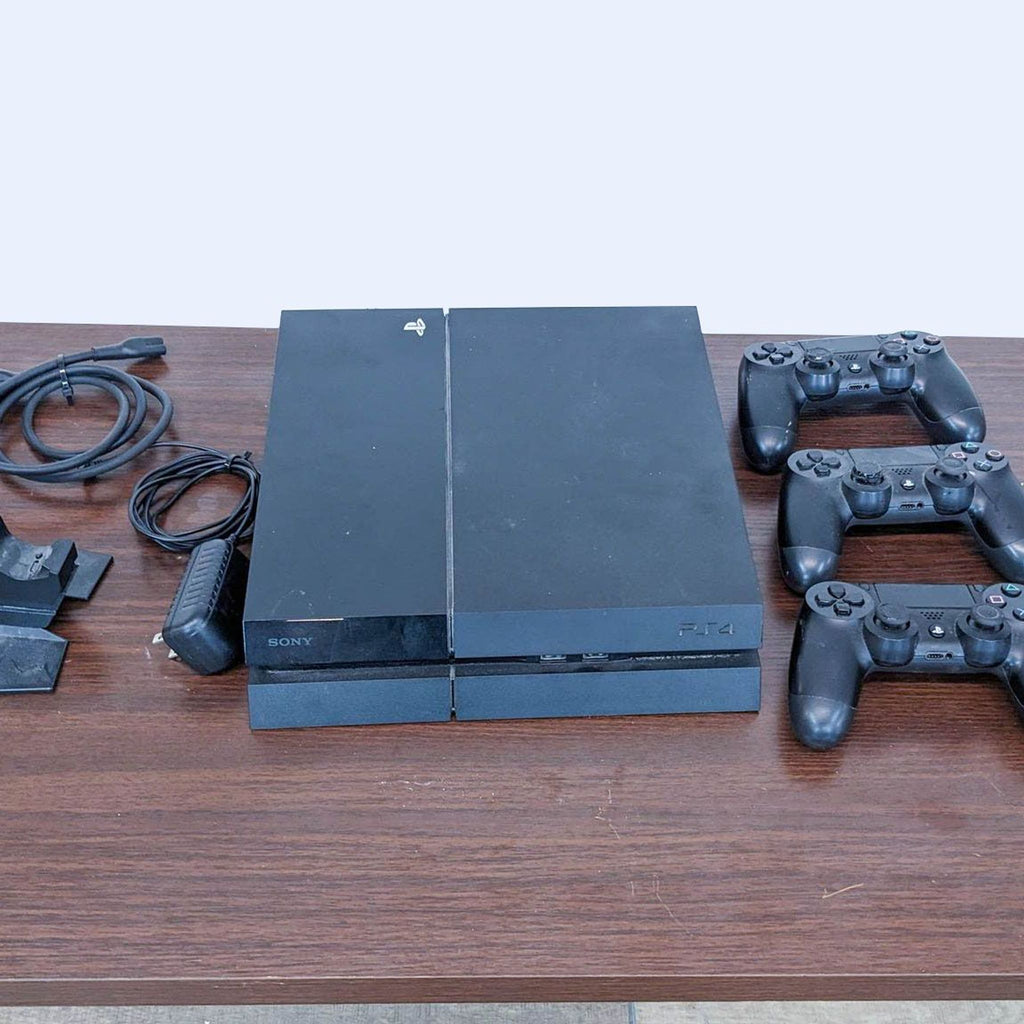 Sony PlayStation 4 console with two controllers and cables on a wooden surface, used condition.