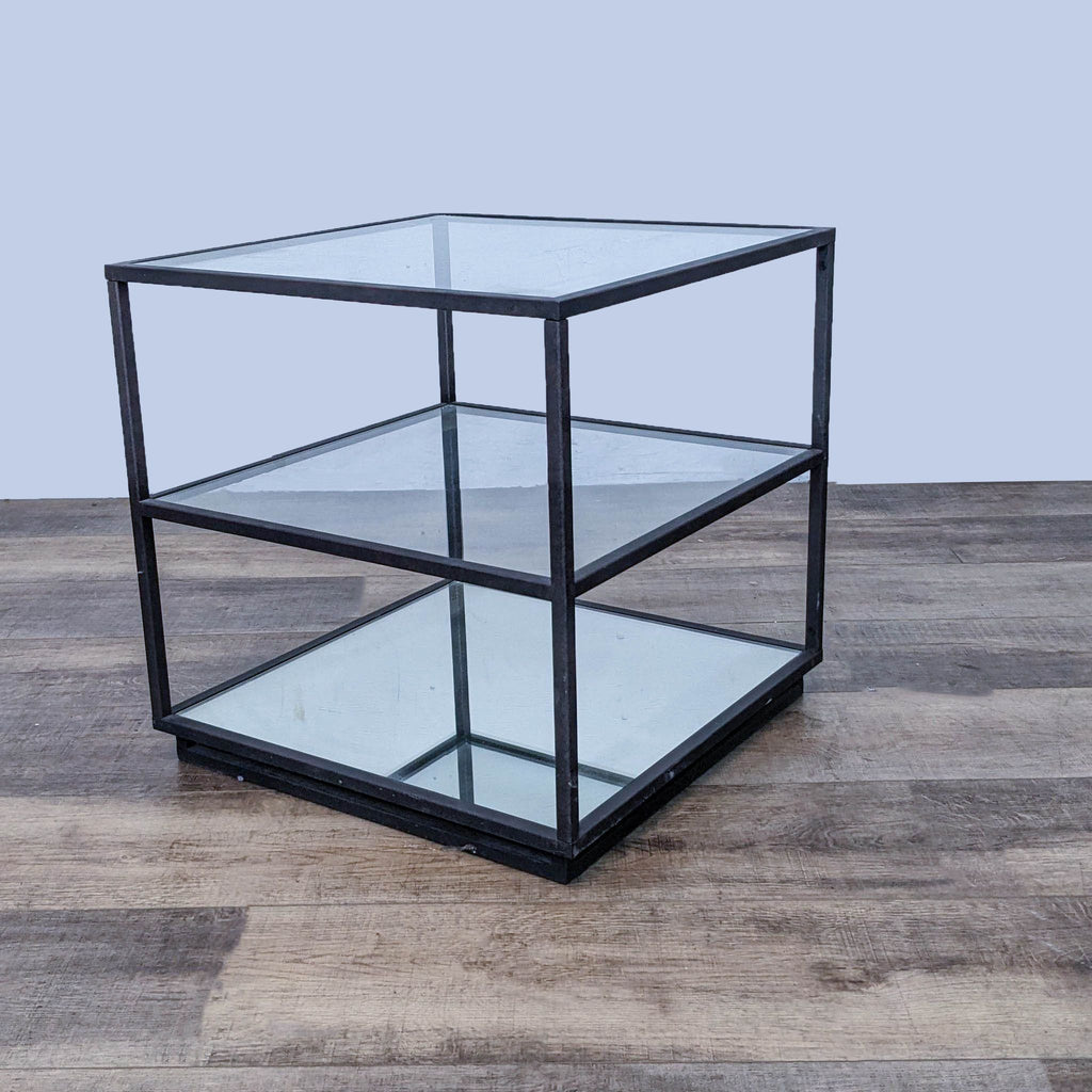 Metal and glass Reperch end table with three levels, including a reflective base shelf, against a wooden flooring background.