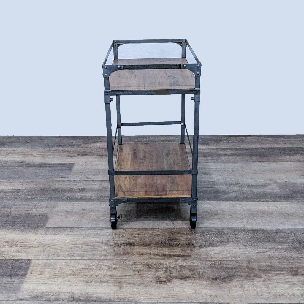 Cost Plus two-tiered serving cart with wood shelves and metal structure, viewed from the front, on a textured floor.
