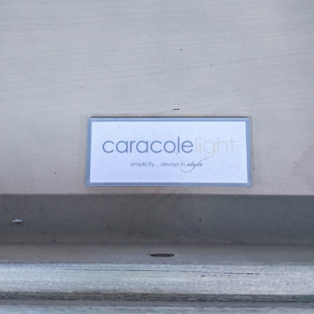 Label from Caracole brand on a piece of wood furniture with the text "caracolelight - simplicity... always in style".