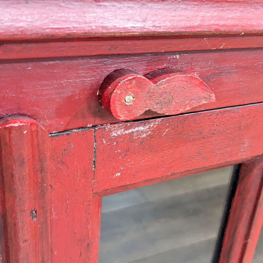 Close-up of the red cabinet's latch and wood texture detail.