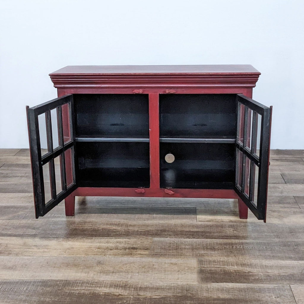 Open red cabinet with glass-paneled doors showcasing interior shelves.
