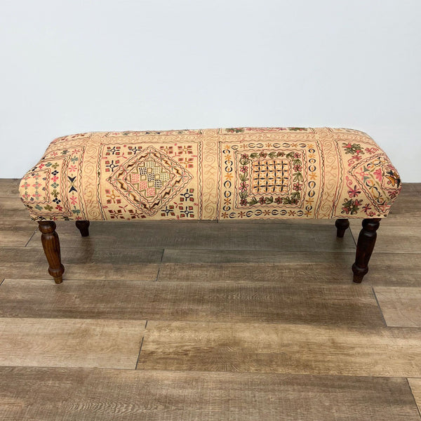 Whimsical fabric bench with dark wooden legs, featuring intricate patterns.
