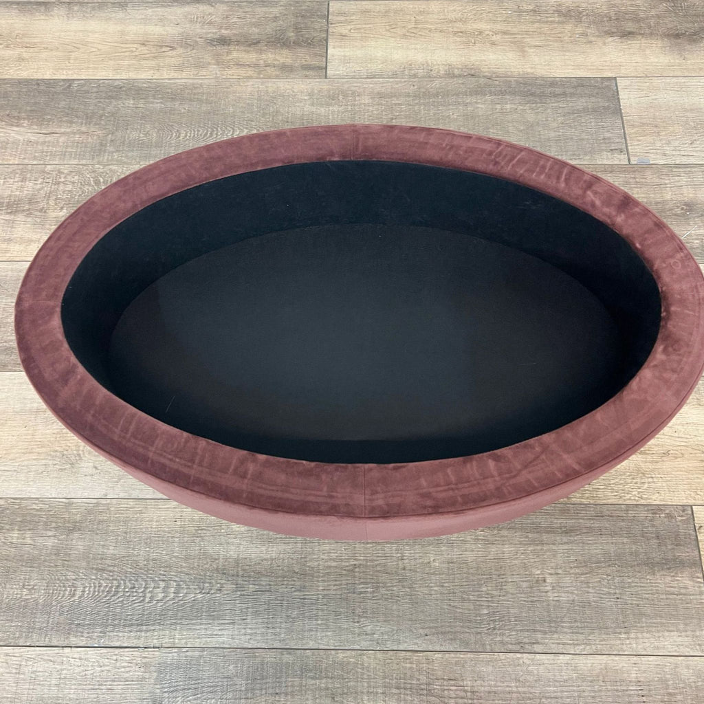 Interior view of a velvet storage ottoman, highlighting its oval shape and storage capacity.