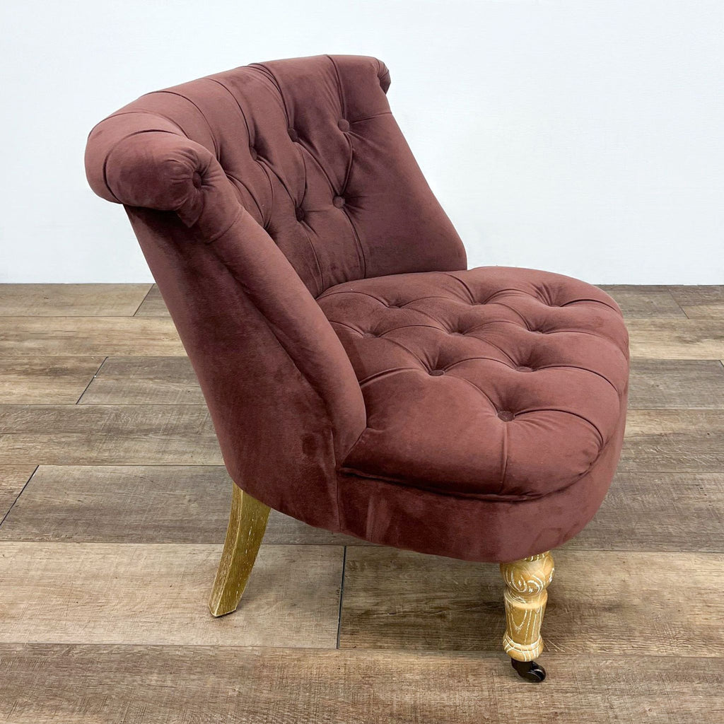 Elegant velvet Cost Plus lounge chair with button detailing and ornate wooden legs featuring caster wheels.