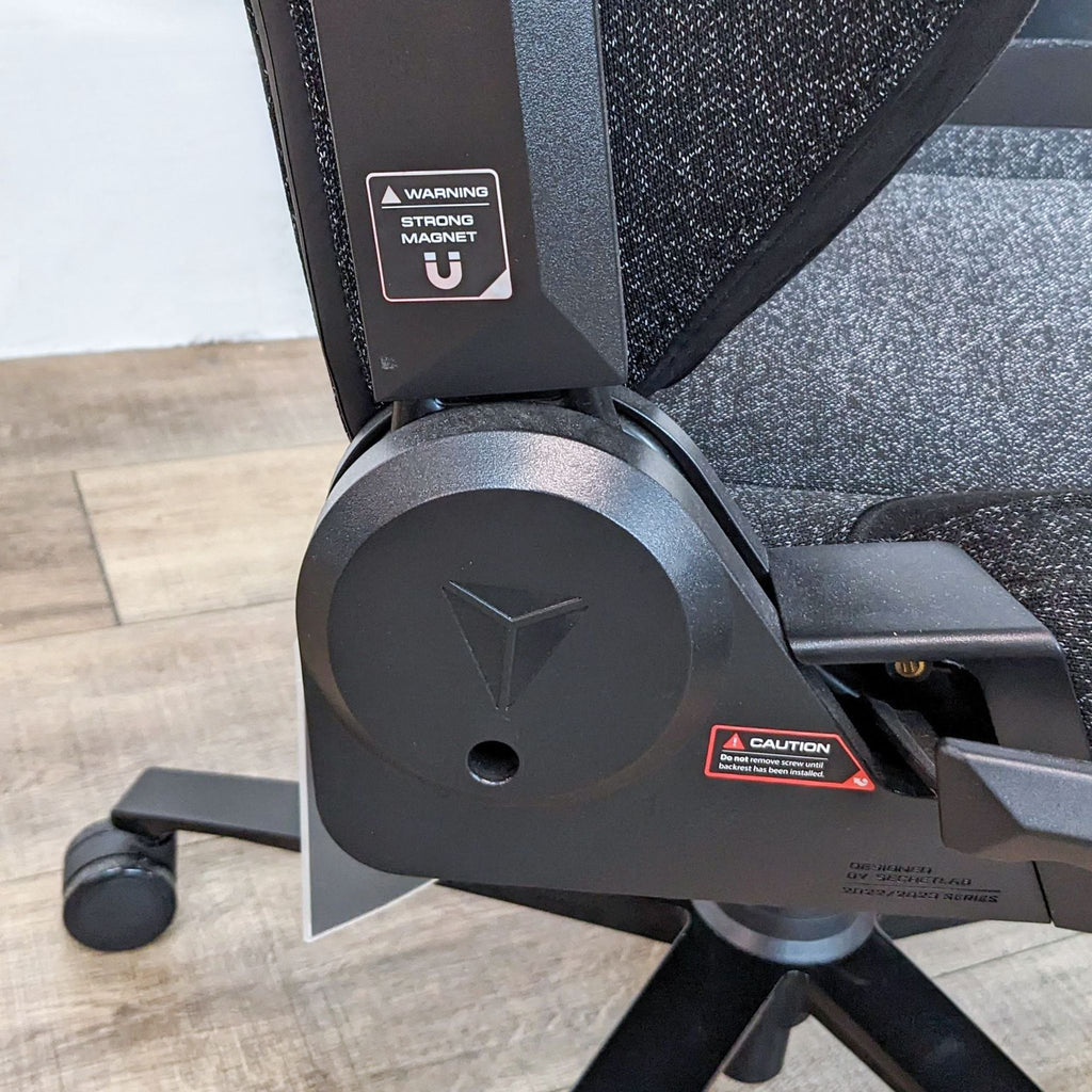 Close-up of the Titan Evo chair’s hydraulics and warning labels, highlighting its construction details.