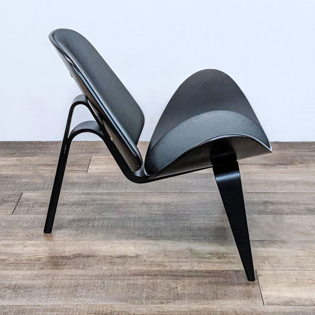 Rear view of an ergonomic Shell lounge chair by Carl Hansen & Son, highlighting its curved back and wooden accents.