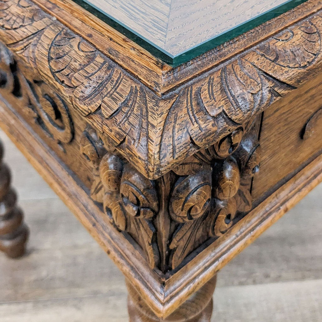 2. Close-up of a Reperch oak table's corner showing detailed carvings and the edge of the glass table top.