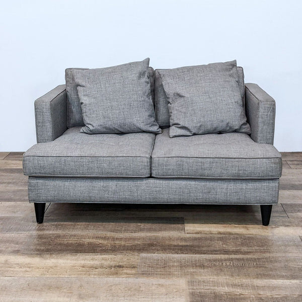 Gray tufted loveseat with narrow arms and dark wooden legs.