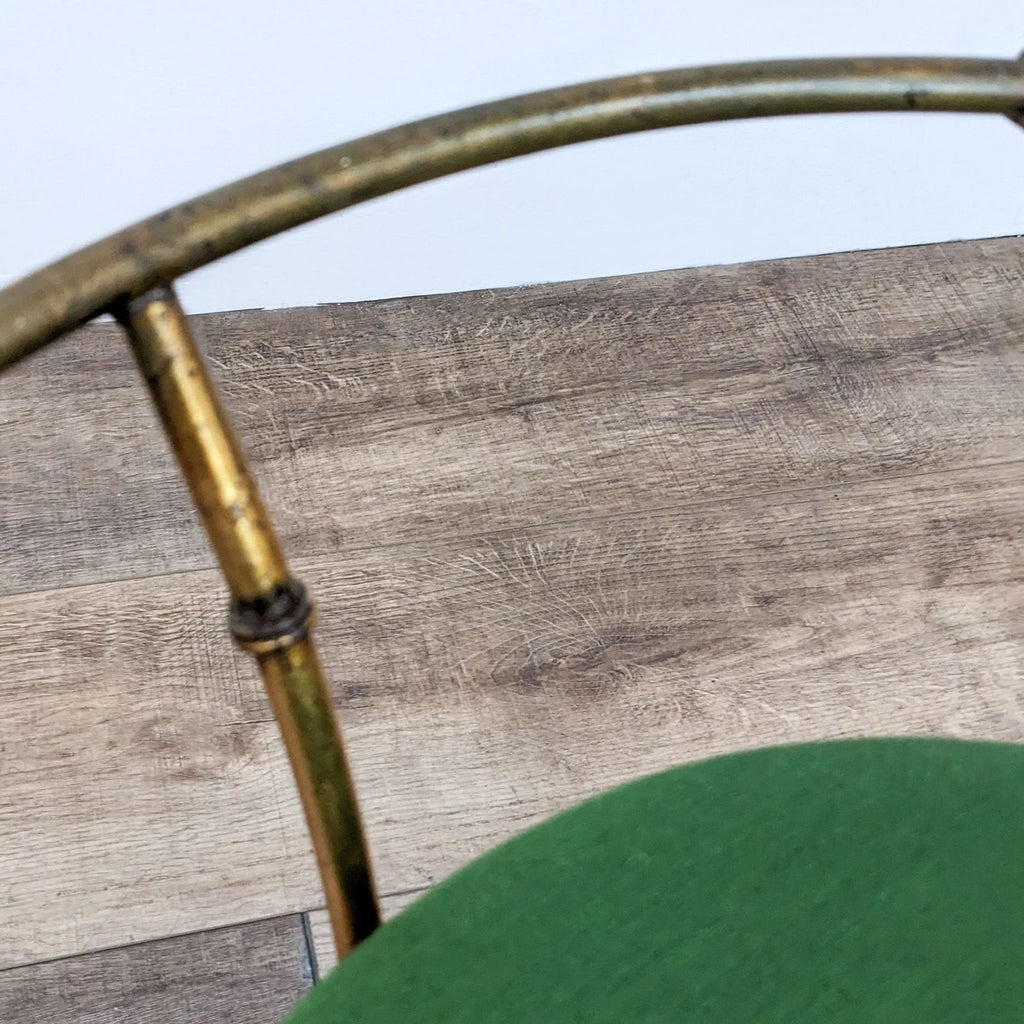 Detail view of vintage stool's gold frame showing texture and design against wooden floor.
